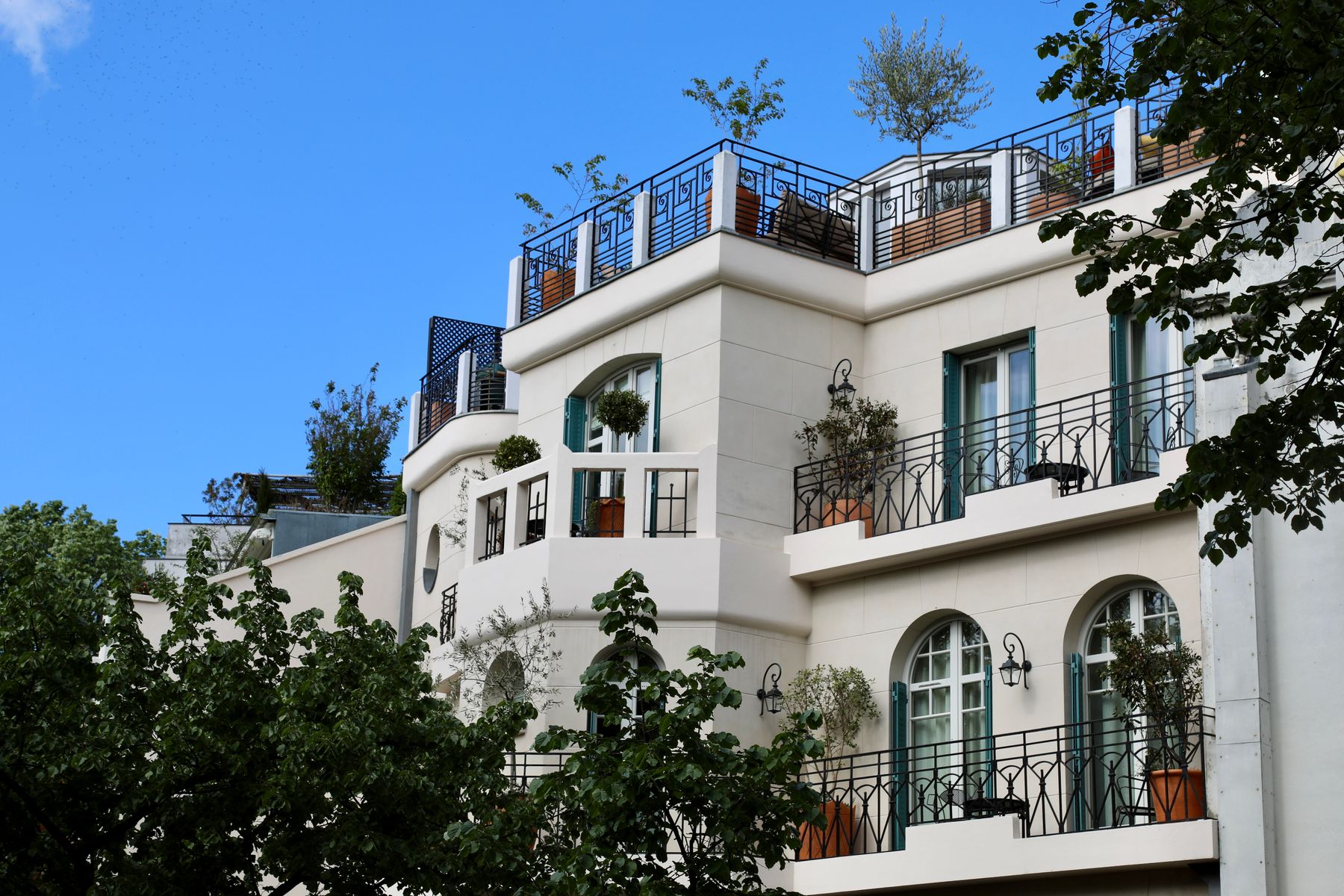 Façade claire d’un immeuble parisien avec des balcons végétalisés sous un ciel bleu